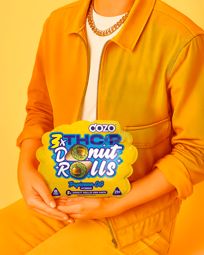 Model in an orange jacket holding a pack of DOZO THC-P Donut Rolls
